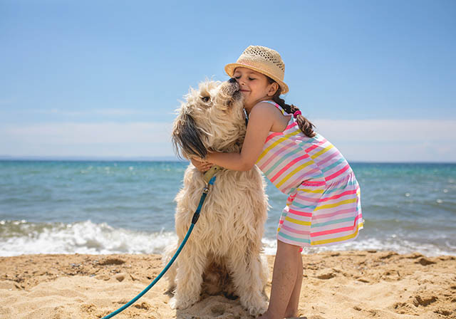 Girl hugging her puppy on the beach at The Grand Strand
