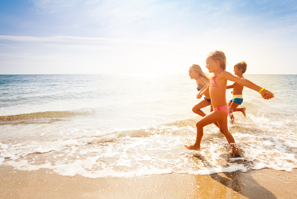 three kids running on the beach
