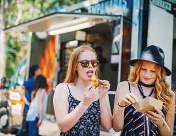 Teenage girls eating food from a food truck