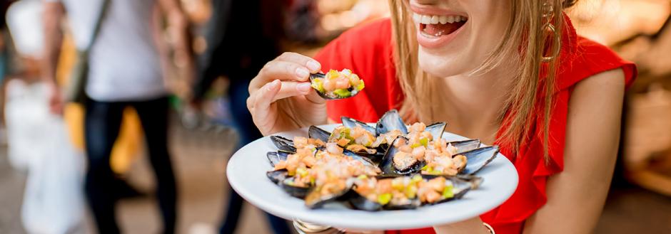 Woman eating mussels at a seafood market