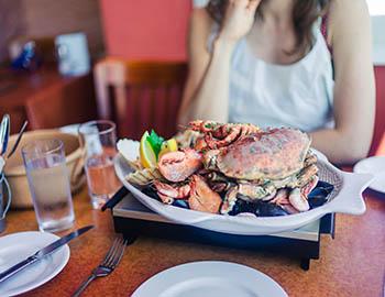 Woman sitting at table in front of a big plate of seafood